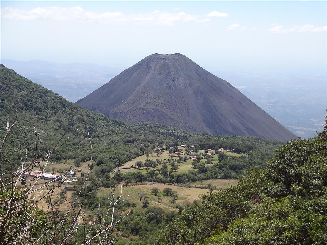 Volcán de forma cónica rodeado de bosque bajo un cielo azul, en Santa Ana, El Salvador